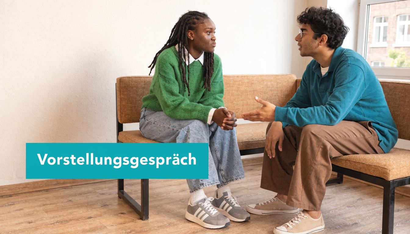 Ein junges Paar sitzt auf einem Sofa und führt ein freundliches Gespräch in einer Büroumgebung.
