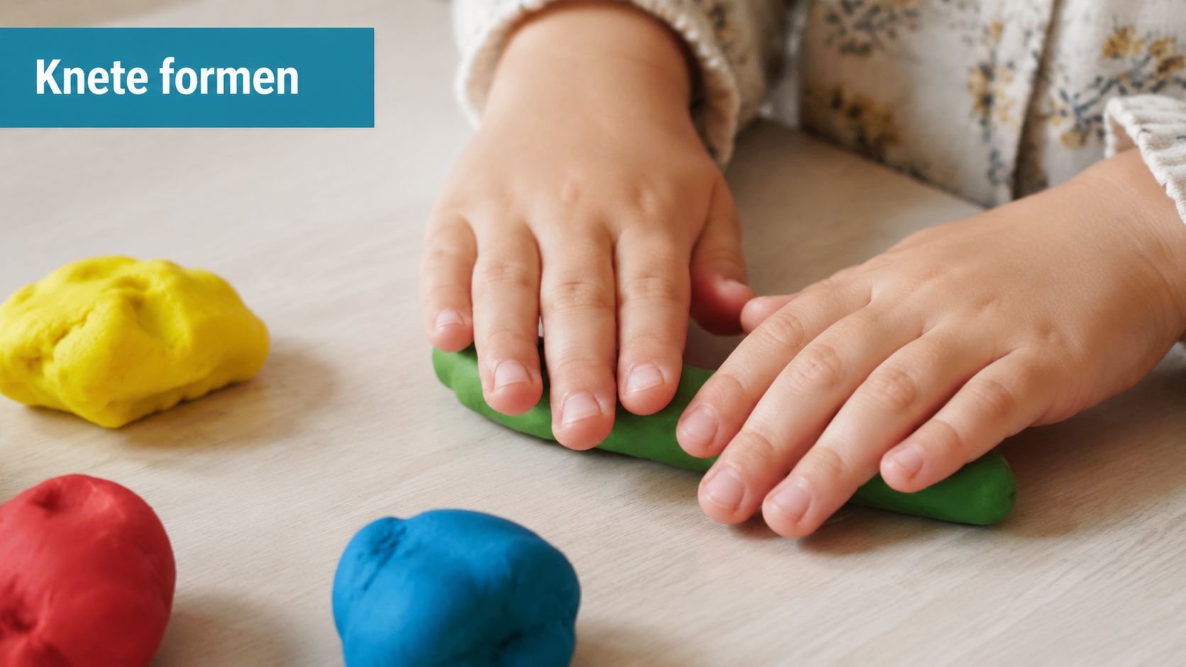 Ein Kind formt mit den Händen eine grüne Knetrolle auf einem hellen Tisch neben weiteren bunten Knetklumpen.