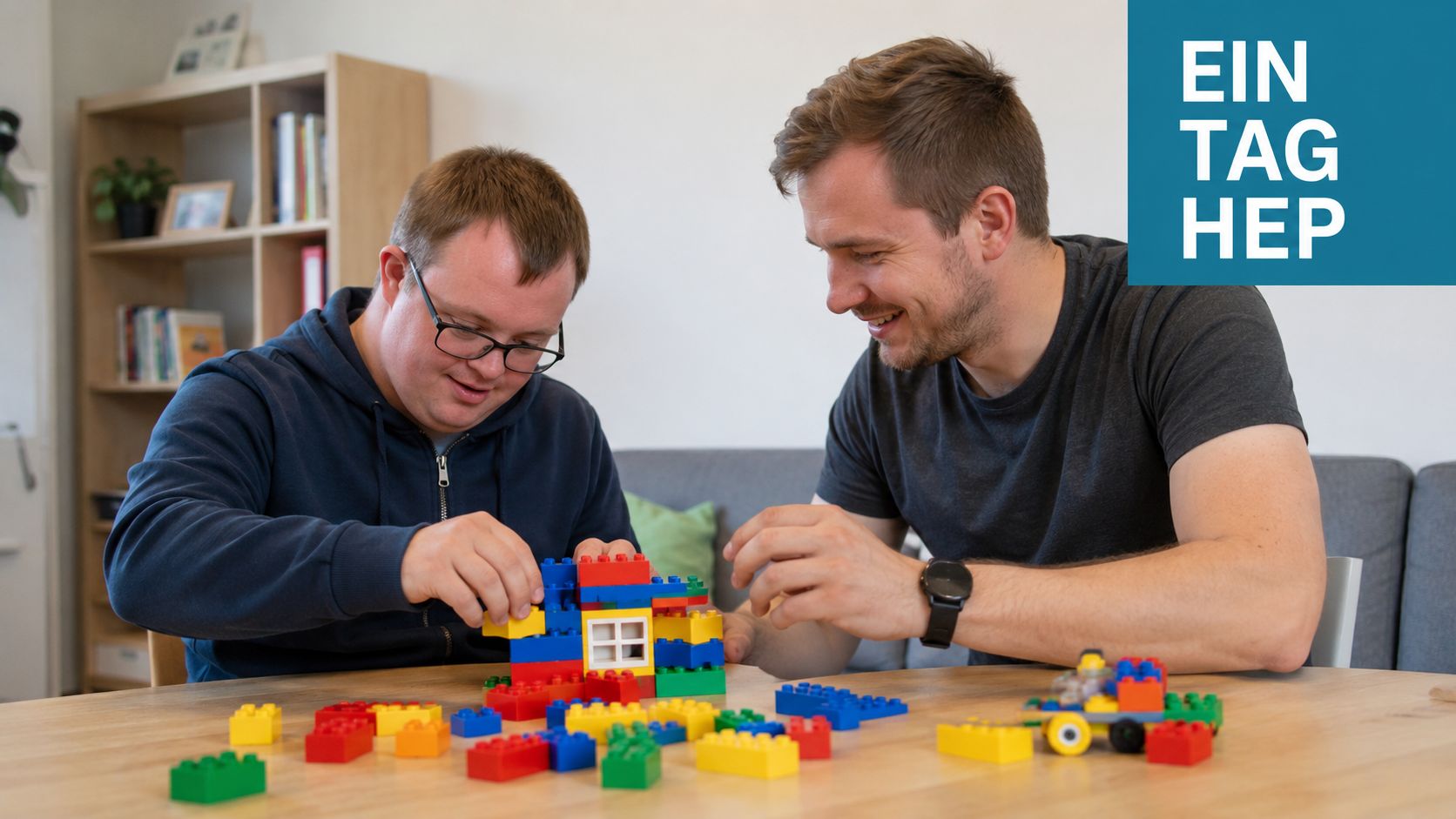 Ein Heilerziehungspfleger baut gemeinsam mit einem jungen Mann mit Down-Syndrom ein Haus aus bunten Kunststoff-Bausteinen am Tisch.